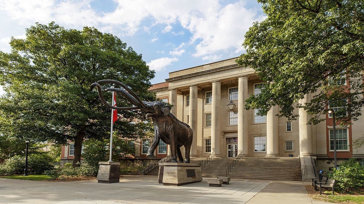 Exterior of Morrill Hall with Archie statue in front and green trees