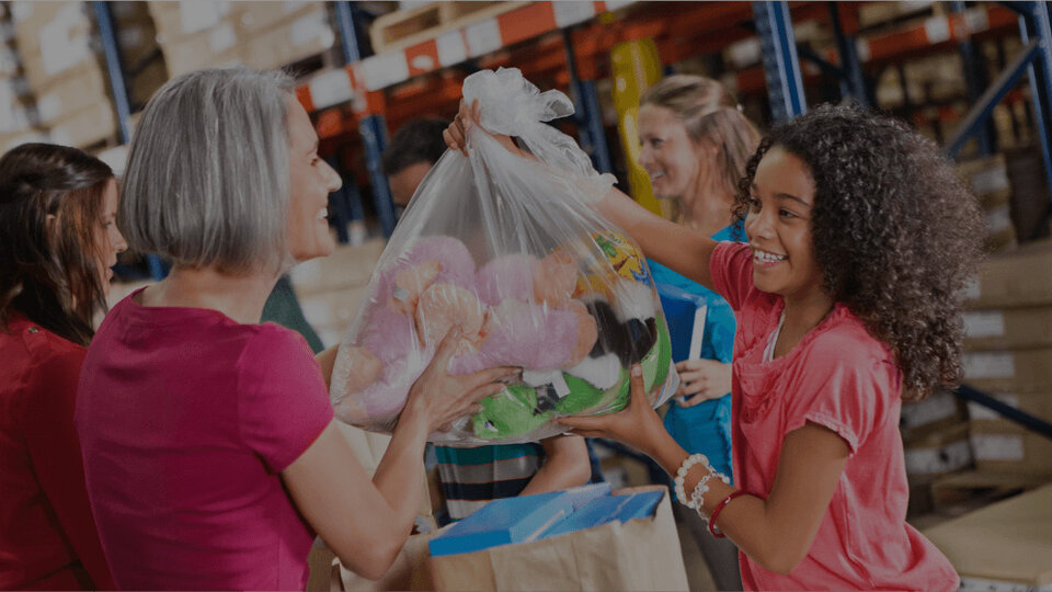 Little girl giving bag of stuffed animals to older lady