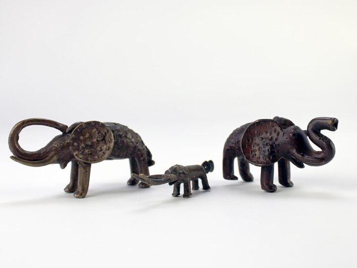 A set of three metal elephant weights, two large and one small.