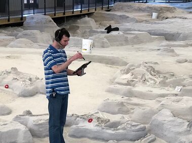 Researcher with headset and mic on digsite with iPad